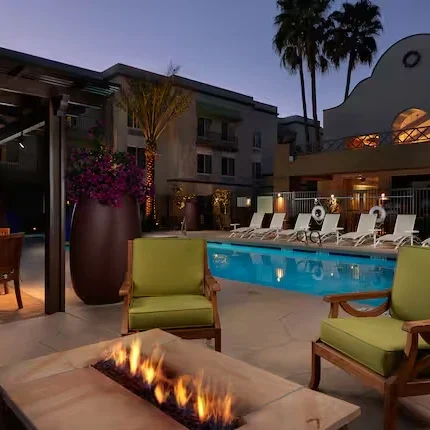 Outdoor pool with lounge chairs and fire pit at Hampton Inn & Suites Scottsdale at night