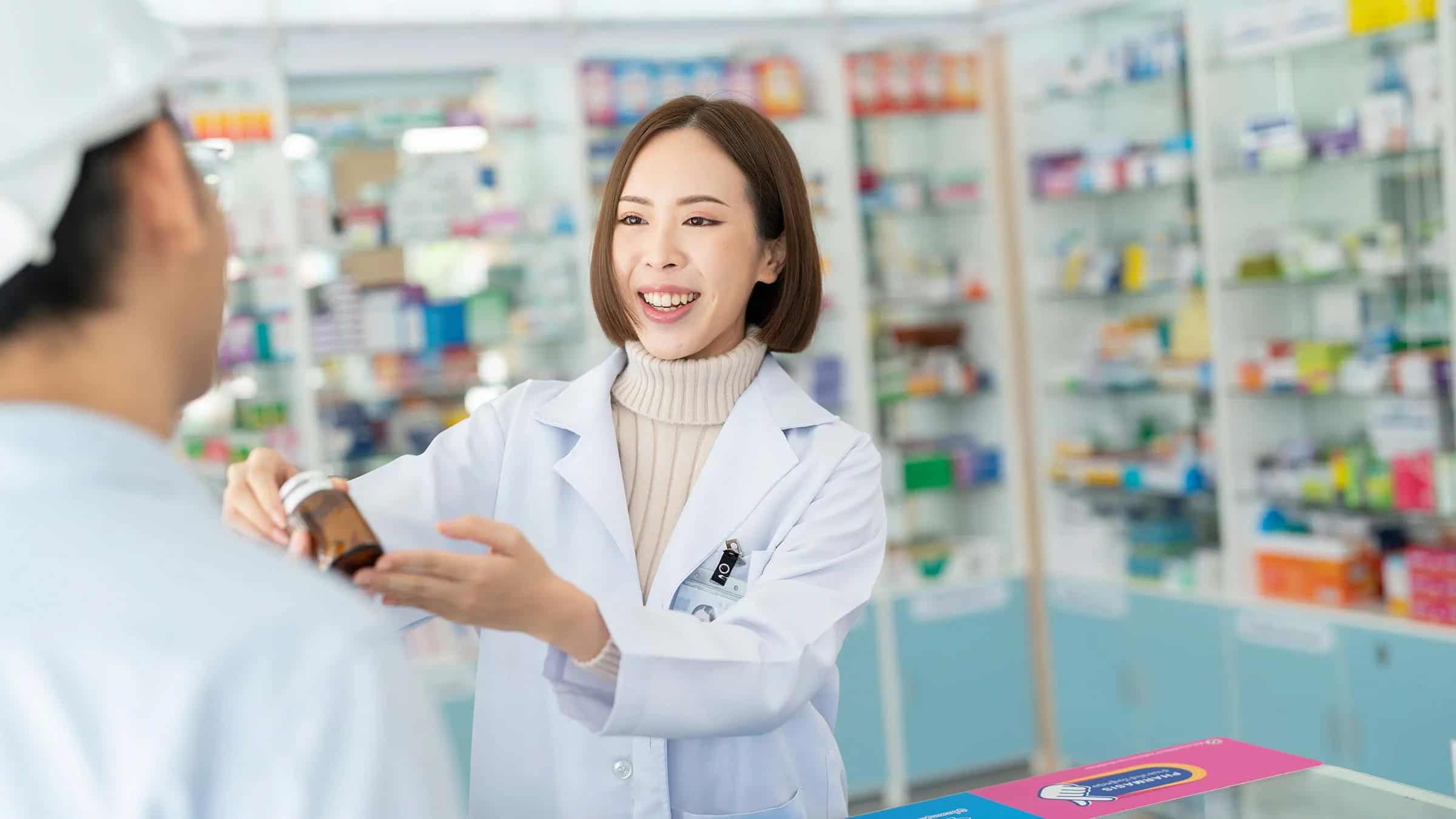Pharmacist-customer A friendly pharmacist handing medication to a customer at Walgreens, illustrating personalized service and patient support in a pharmacy setting.
