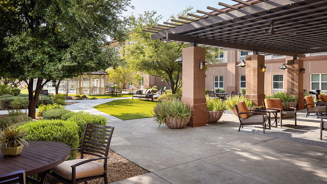 Peaceful outdoor patio and garden area at Belmont Village Scottsdale, offering a relaxing environment for older adults receiving on-site medical care.