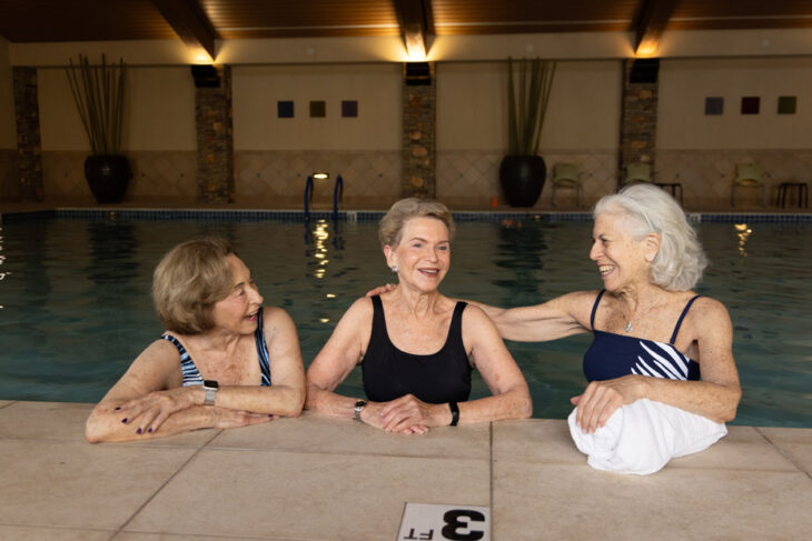 Three senior women at Sagewood’s indoor pool enjoying social wellness, active aging, and community connection in Phoenix, AZ.