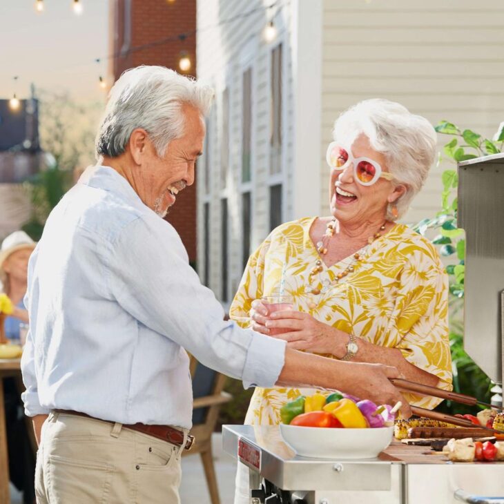 Two older adults enjoying a cheerful barbecue at Sunrise of Scottsdale, reflecting active and joyful community living.