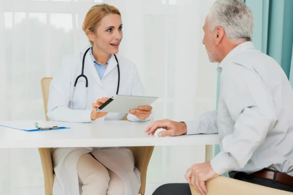 Female physician consulting an older male patient using a digital tablet during a clinic visit