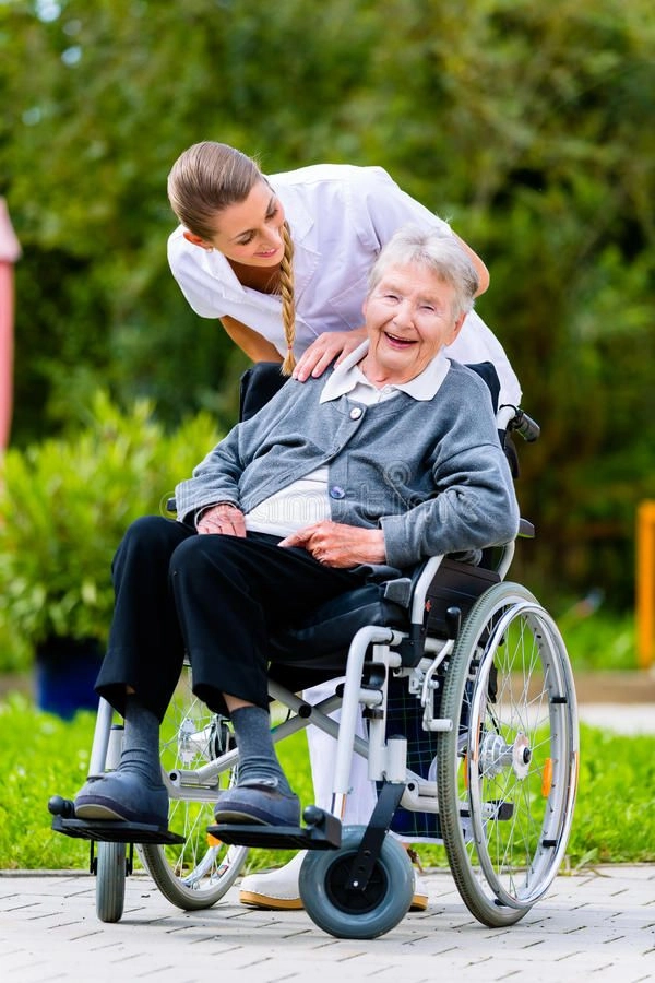 Smiling older woman in wheelchair being supported by a caregiver outdoors in Scottsdale 85258