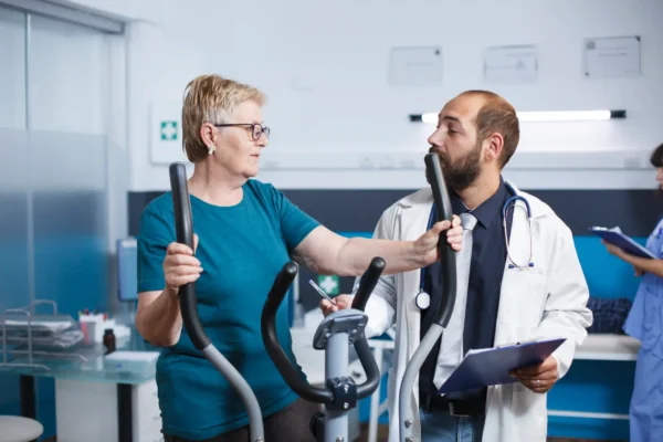 Elderly female patient engaging in physiotherapy exercises under a doctor's supervision.