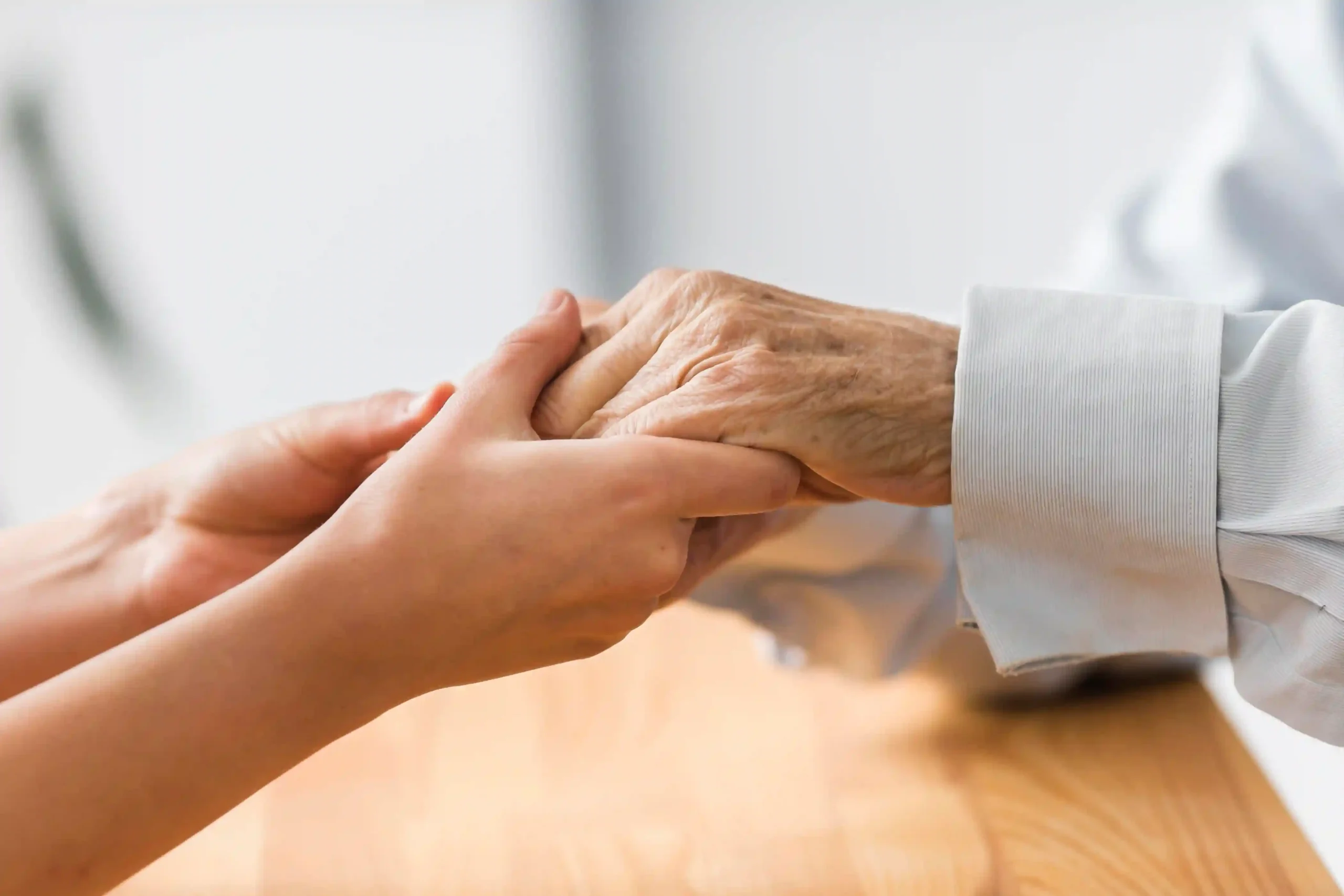Close-up of a caregiver holding an elderly man’s hand during hospice care in Scottsdale’s 85251 ZIP code