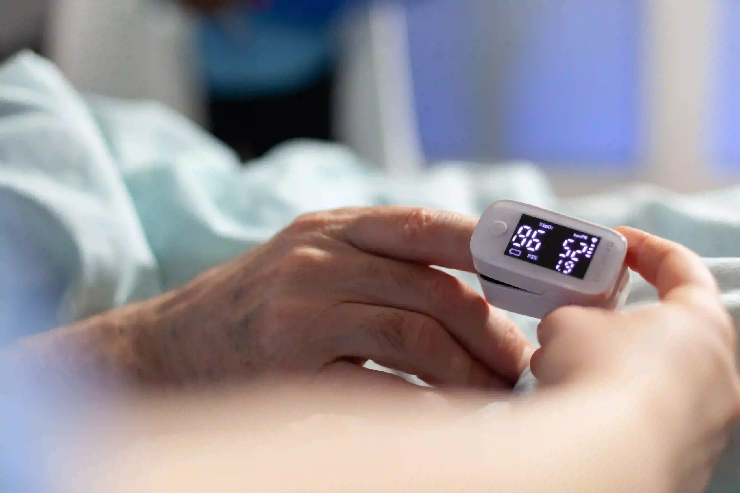 Close-up of a patient’s hand with a pulse oximeter measuring oxygen saturation and heart rate.