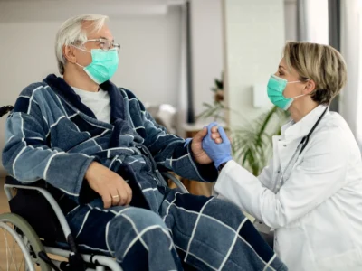 Elderly man in a wheelchair speaking with a masked doctor during a home health care visit in Scottsdale’s 85250 area