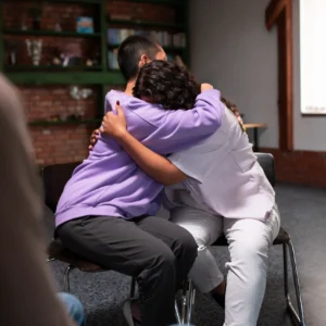 Group hug during grief support session at Casa De La Luz Hospice, illustrating emotional connection and care.
