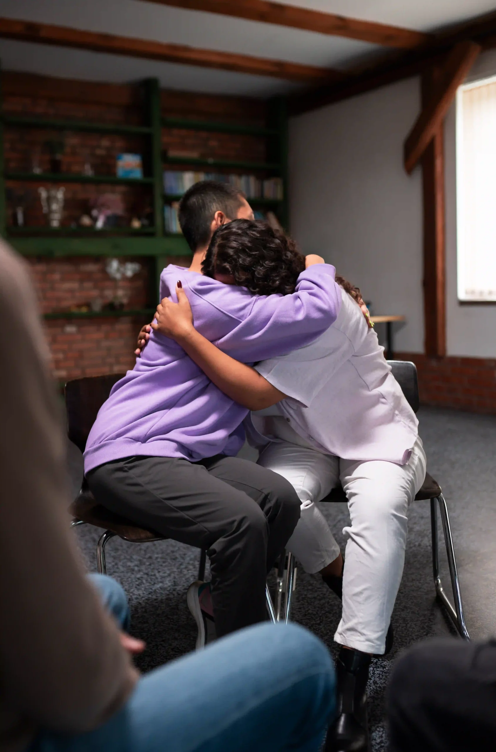 Group hug during grief support session at Casa De La Luz Hospice, illustrating emotional connection and care.