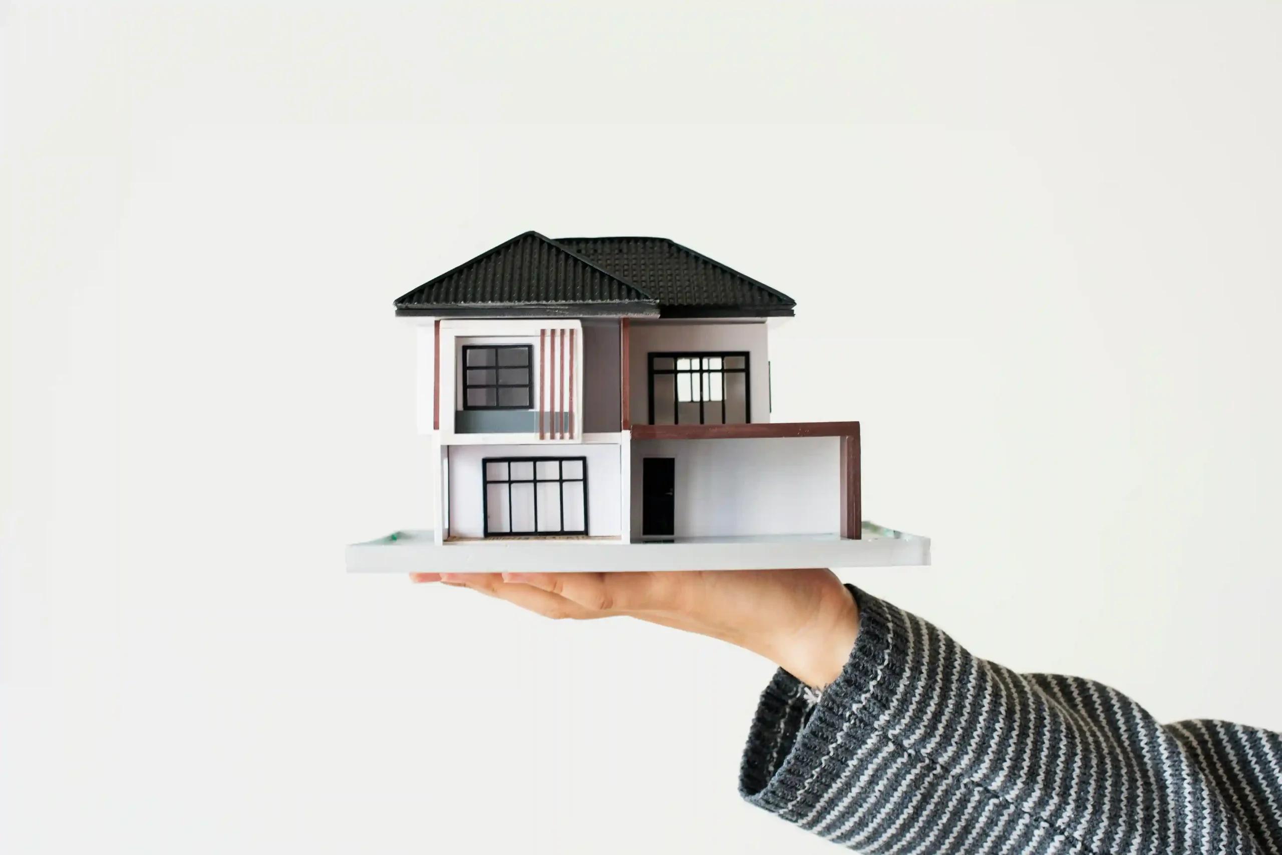 Hand holding a model house symbolizing safe home adaptation for older adults in 85250