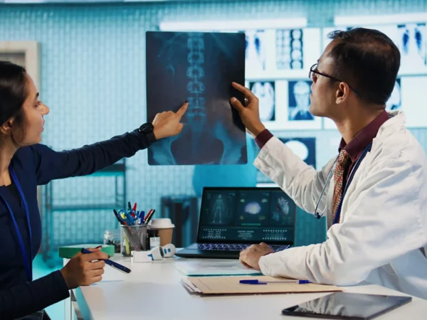 Doctor and nurse discussing spinal X-ray results in a modern clinic.
