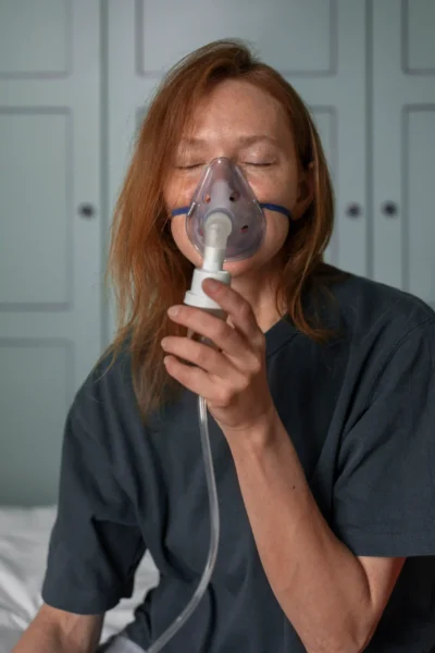 Older woman using nebulizer mask for respiratory treatment at home