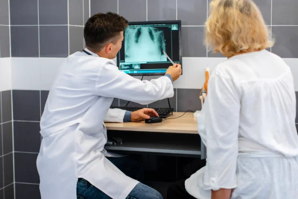 Male doctor reviewing chest X-ray with female patient during diagnostic consultation.
