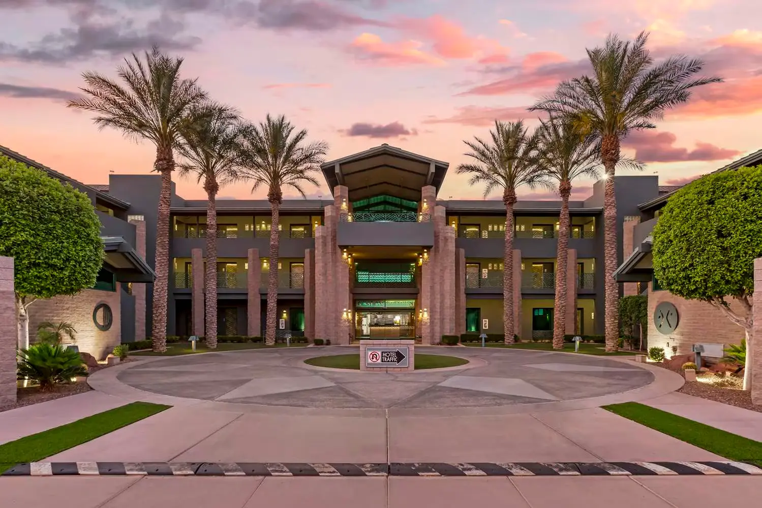 Front exterior of Best Western Plus Sundial hotel in Scottsdale, Arizona, with palm trees and modern architecture at sunset