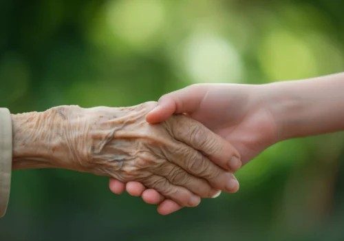 Young caregiver holding hands with an elderly person, symbolizing Dr. Cook’s compassionate in-home healthcare at A Place in the Sun