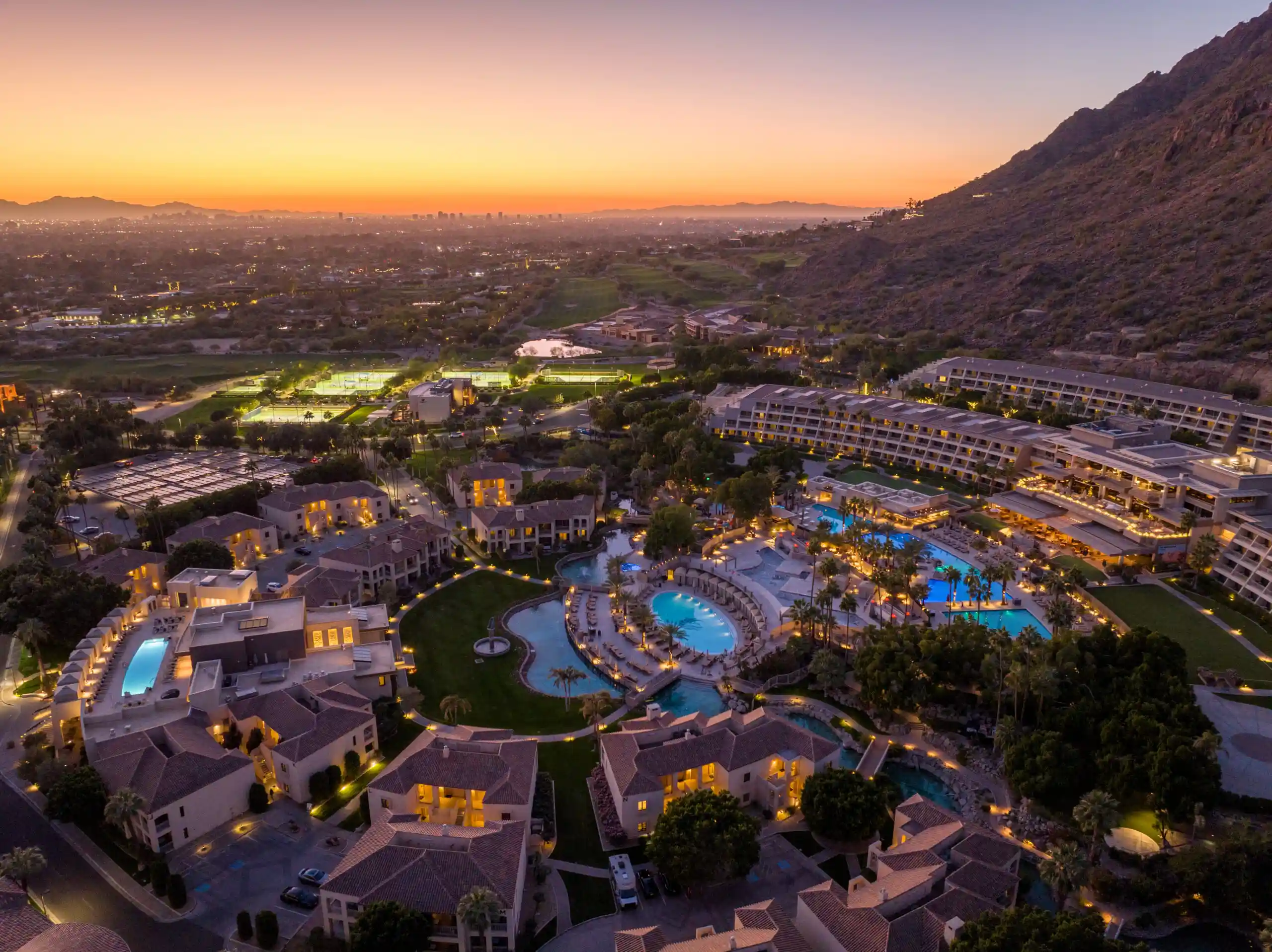 Aerial view of The Phoenician Scottsdale resort at sunset with pools, villas, and Camelback Mountain, highlighting luxury and wellness with Dr. Cook’s medical care.