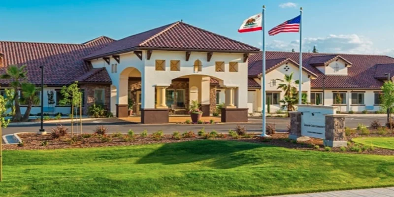 Amber Creek Memory Care Community in Scottsdale with landscaped grounds, front entrance, and American and California flags flying