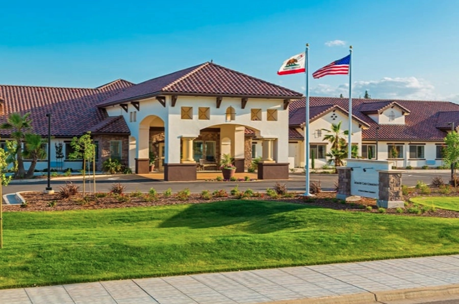 Amber Creek Memory Care Community in Scottsdale with landscaped grounds, front entrance, and American and California flags flying