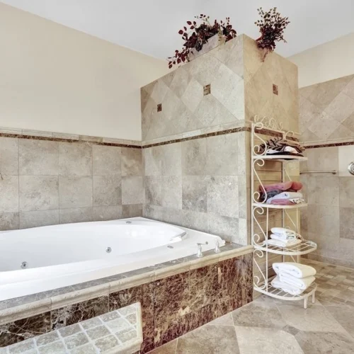 Spacious bathroom at American Dream Home II featuring a large whirlpool tub and tiled shower
