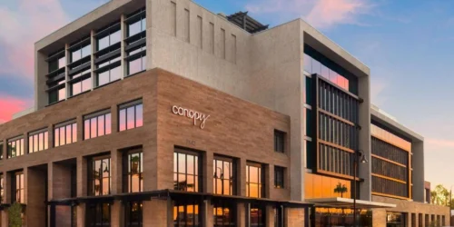 Exterior view of Canopy by Hilton Scottsdale Old Town hotel at 7142 E 1st St with modern architecture and sunset reflection