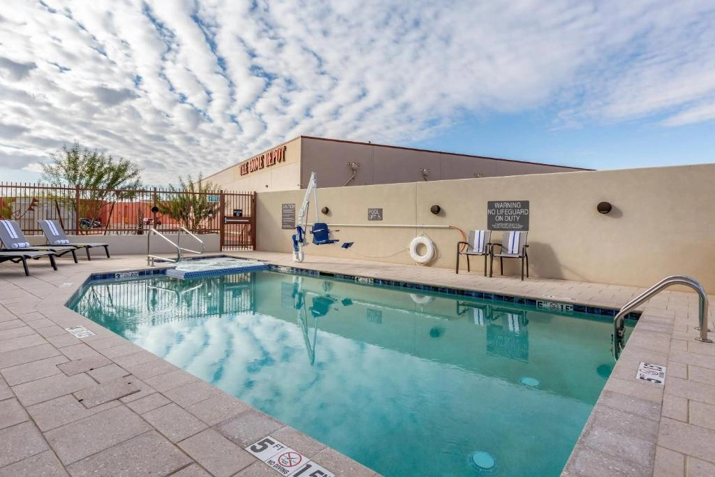 Outdoor hotel pool at Comfort Suites Scottsdale with ADA chair lift, lounge chairs, and clear sky at 9215 E Hummingbird Ln.