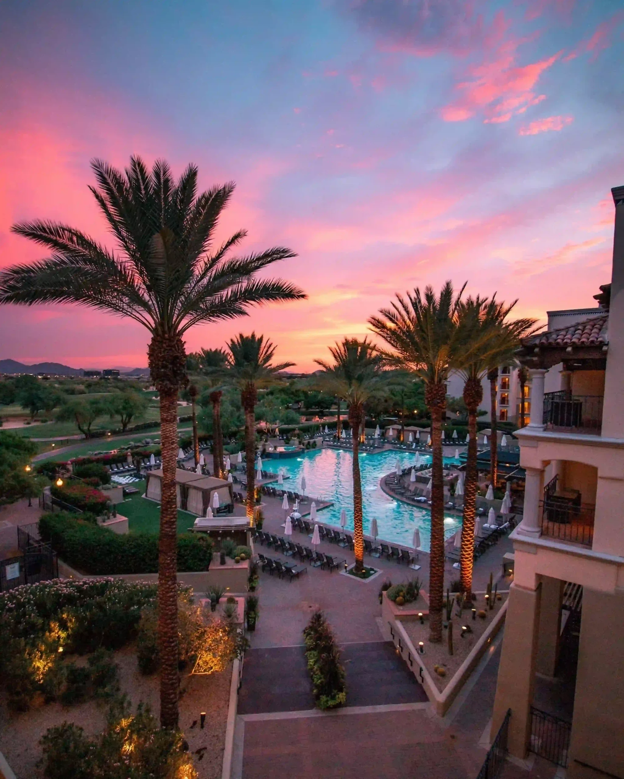 Sunset view of Fairmont Scottsdale Princess resort with palm trees, pool, and illuminated pathways