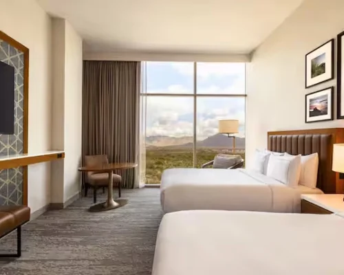 Modern double guest room with mountain view at Hilton North Scottsdale at Cavasson, featuring large windows and desert-inspired décor