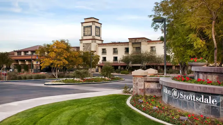 Exterior view of Hilton Scottsdale Resort & Villas on North Scottsdale Road with palm trees and evening lights