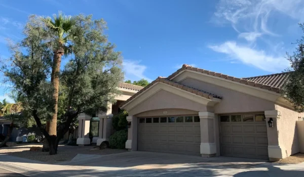 Front exterior of Assisted Living of Scottsdale II on East Shea Boulevard, Scottsdale, showing driveway, garage, and desert landscaping with palm and olive trees.