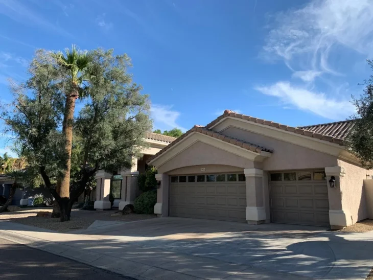 Front exterior of Assisted Living of Scottsdale II on East Shea Boulevard, Scottsdale, showing driveway, garage, and desert landscaping with palm and olive trees.