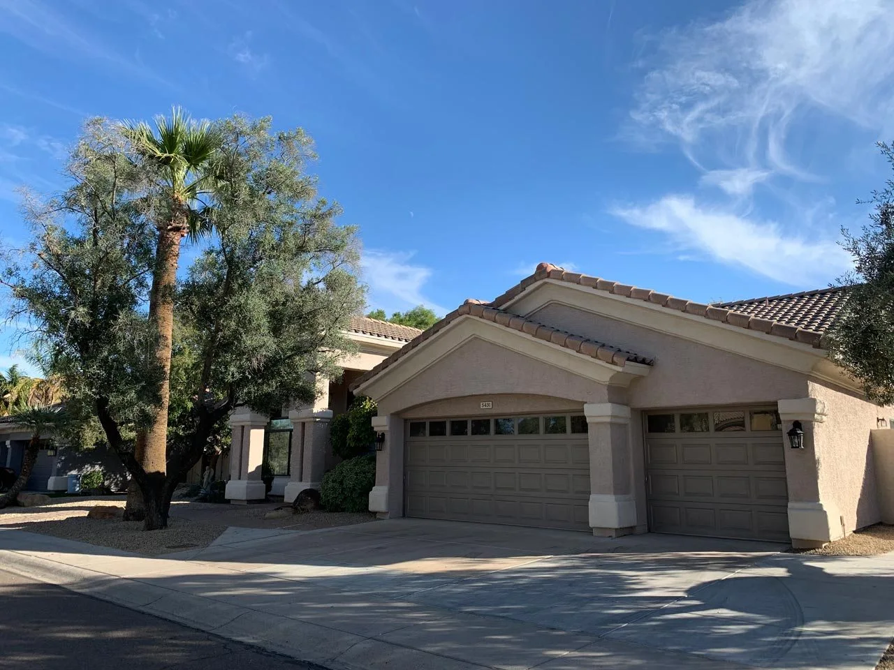 Front exterior of Assisted Living of Scottsdale II on East Shea Boulevard, Scottsdale, showing driveway, garage, and desert landscaping with palm and olive trees.