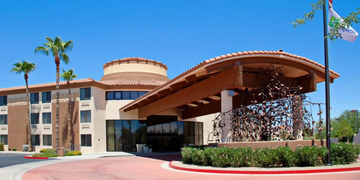 Exterior of Holiday Inn Express Scottsdale North with palm trees and terracotta-roof entrance under clear blue sky.