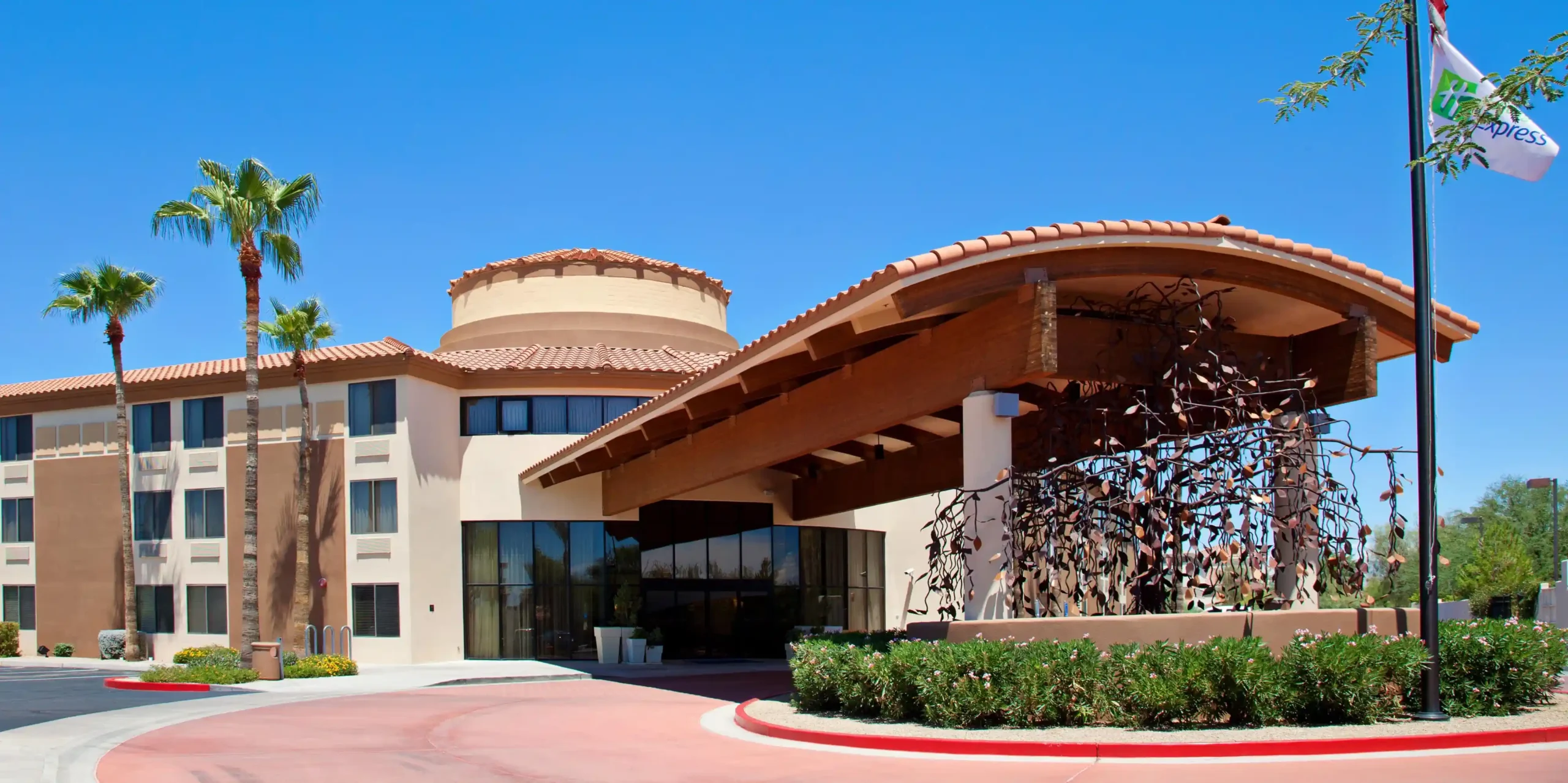 Exterior of Holiday Inn Express Scottsdale North with palm trees and terracotta-roof entrance under clear blue sky.