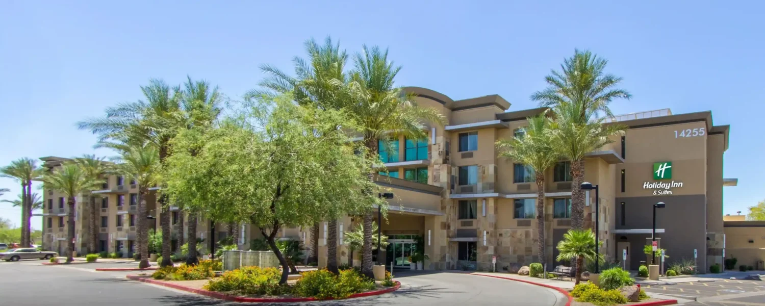 Front exterior of Holiday Inn & Suites Scottsdale North – Airpark with palm trees and driveway
