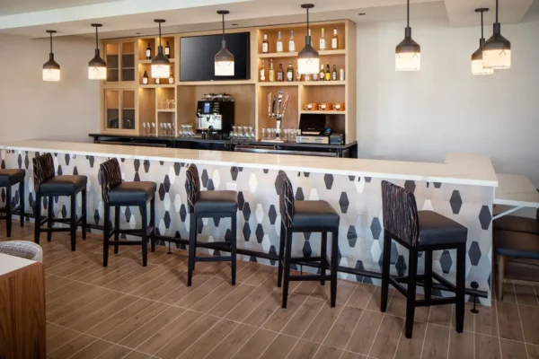 Modern hotel bar at Hyatt Place Scottsdale – North with high stools, pendant lighting, and a backlit beverage wall.