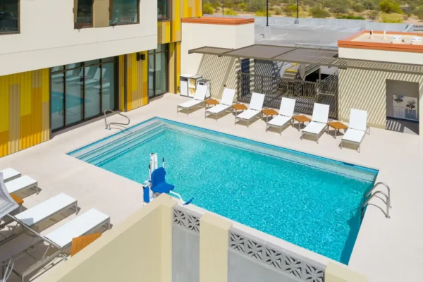 Outdoor pool area at Hyatt Place Scottsdale – North with lounge chairs, sun deck, and accessible pool lift.