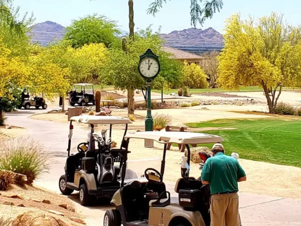 Golf carts parked near a green clock surrounded by desert trees and mountains at McDowell Mountain Golf Club in Scottsdale, Arizona.
