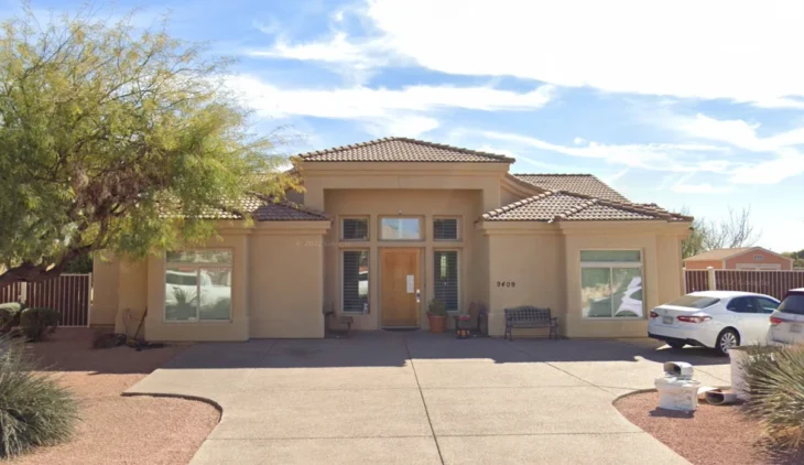 Exterior view of Bloomfield House assisted living facility at 9409 East Bloomfield, Scottsdale. A single-story beige stucco home featuring a tile roof, desert landscaping, and a welcoming entrance under a sunny Arizona sky