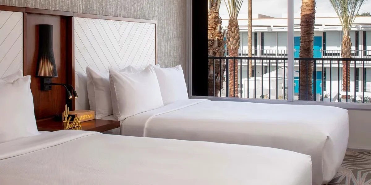 Bright double guestroom at Hotel Adeline with two beds and balcony overlooking the courtyard