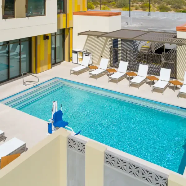 Outdoor swimming pool at Hyatt House North Scottsdale with lounge chairs, shaded seating, and an accessible pool lift