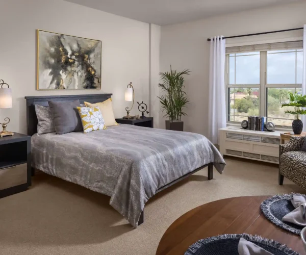 Private assisted living bedroom at Sunrise of North Scottsdale in Scottsdale, AZ with large window, modern decor, and dining nook.