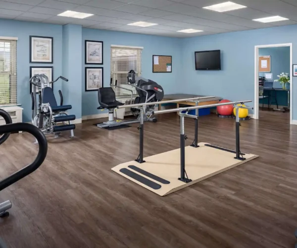 On-site physical therapy and fitness room at Sunrise of North Scottsdale with rehab equipment, parallel bars, and exercise machines.