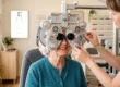 Older woman having an eyesight exam through a phoropter in a bright optometry office